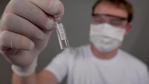 Vial con una vacuna contra el virus y el coronavirus, un hombre tiene en sus manos — Vídeos de Stock