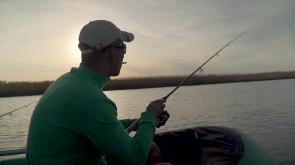 Pescatore pesca su un lago al tramonto, vista dal retro — Video Stock