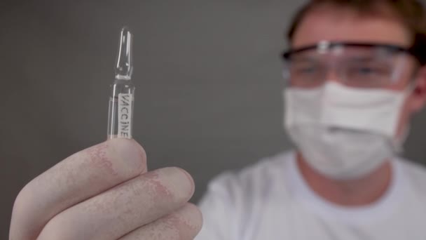 Injekční lahvička s vakcínou proti viru a koronaviru, muž drží v rukou — Stock video