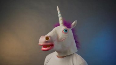 Tek boynuzlu at maskeli adam koruyucu bir maske takıyor.