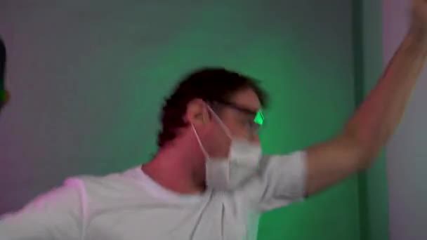 Védőmaszkos férfi és szemüveges táncol a hangszóróval a kezében. — Stock videók