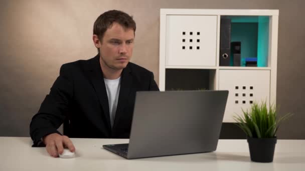 Человек сидит за столом работает на ноутбуке — стоковое видео