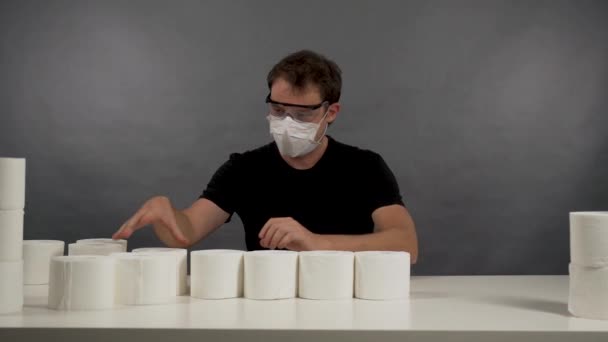 L'homme en masque de protection et des lunettes pour construire une pyramide en papier toilette — Video