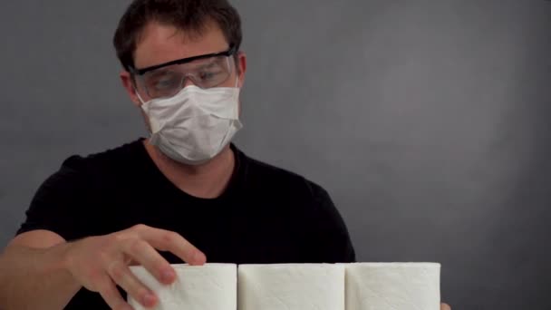 O homem de máscara protetora e óculos para construir uma pirâmide a partir de papel higiênico — Vídeo de Stock