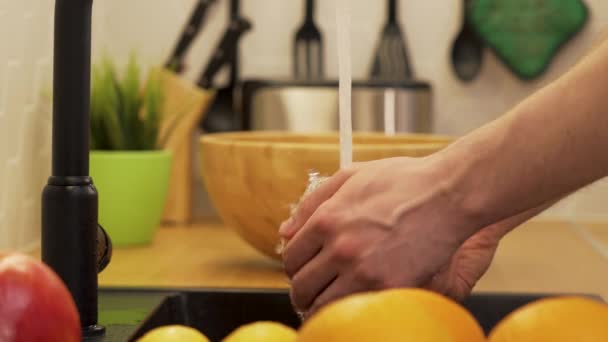 Un hombre lava las naranjas bajo el agua corriente — Vídeo de stock