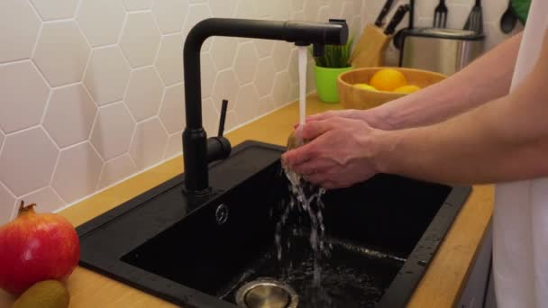 Muž umývá pod tekoucí vodou kiwi — Stock video