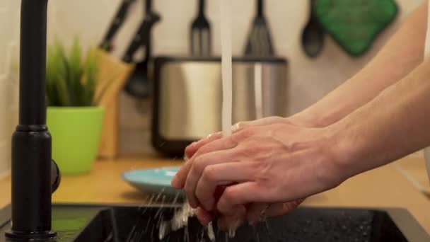 Een man wast onder stromend water de tomaten — Stockvideo