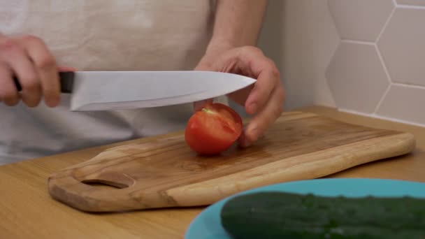 Um homem corta um tomate em uma tábua de cortar — Vídeo de Stock