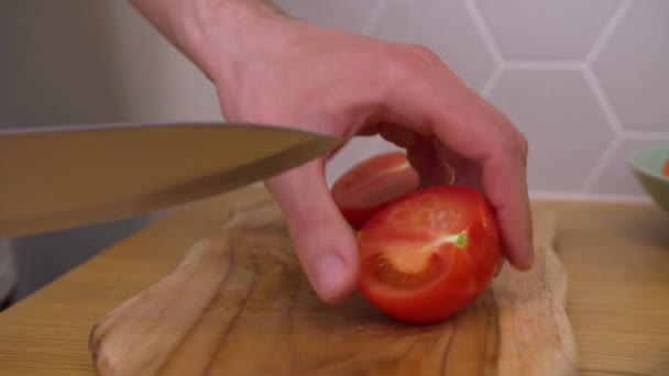 Un hombre corta un tomate en una tabla de cortar — Vídeos de Stock