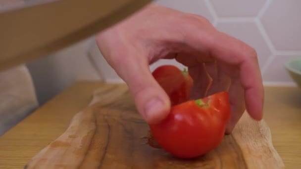 Een man snijdt een tomaat op een snijplank — Stockvideo