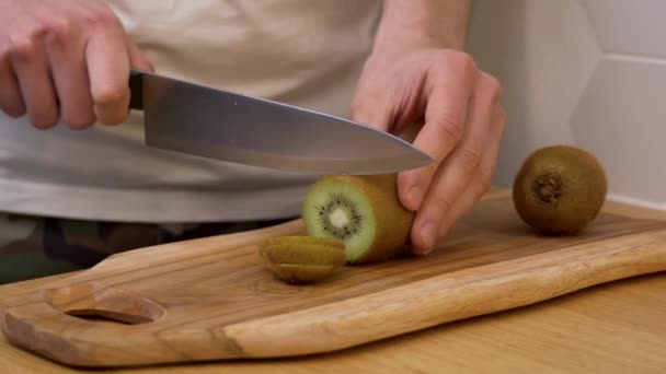 Homem corta fatias de kiwi em uma tábua de corte — Vídeo de Stock