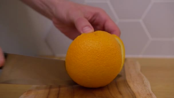 O homem corta a laranja e corta-a em cunhas — Vídeo de Stock