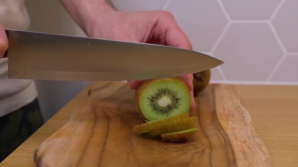 Homem corta fatias de kiwi em uma tábua de corte — Vídeo de Stock