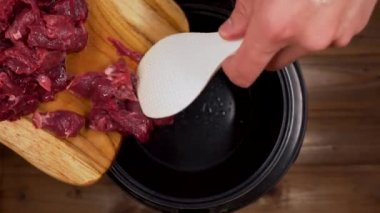 Adam dilimlenmiş eti bir spatulayla fırına atıyor.