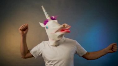 Maskeli adam. Tek boynuzlu at başını sallıyor.