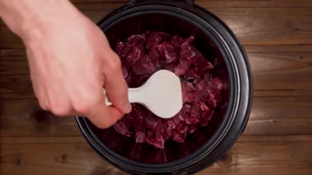 Un hombre cocina la carne en una olla de cocción lenta — Vídeo de stock