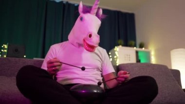 Maskeli bir adam evde oturup Hapi davulunu çalar.