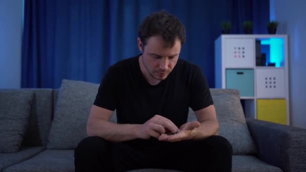 Muž sedící a počítající peníze na gauči, velmi málo z nich — Stock video