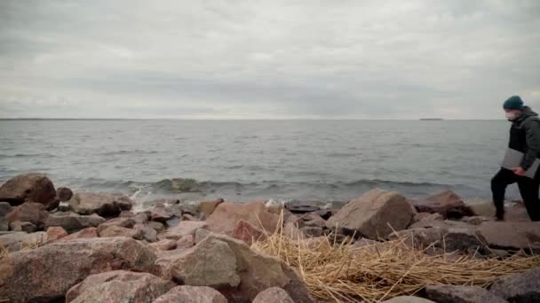 Un hombre camina por la playa con un portátil en la mano — Vídeo de stock