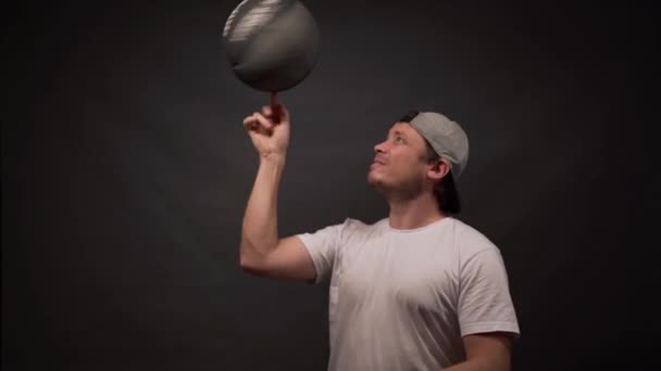 The man turns on his finger basketball on grey background — Stock Video