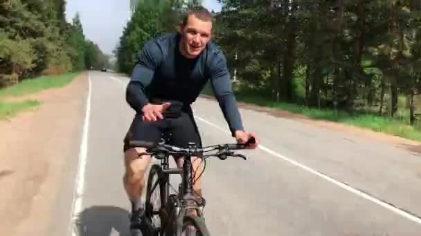 Ein Mann fährt gut gelaunt Fahrrad und zeigt Muskeln — Stockvideo