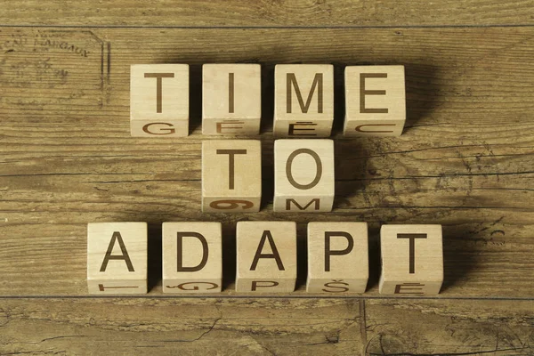 Time to adapt text on cubes on wooden background — Stock Photo, Image