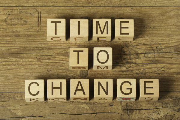 Time to change text on a wooden cubes on a wooden background