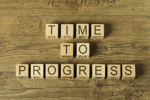 time to progress text on wooden cubes on a wooden background