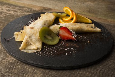 ahşap arka plan üzerinde koyu bir plaka üzerinde meyve ile Pancakes