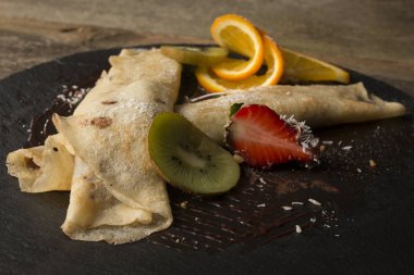 ahşap arka plan üzerinde koyu bir plaka üzerinde meyve ile Pancakes