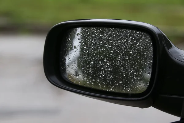 驾着爱车在雨-雨天侧后视镜上的雨滴 免版税图库图片