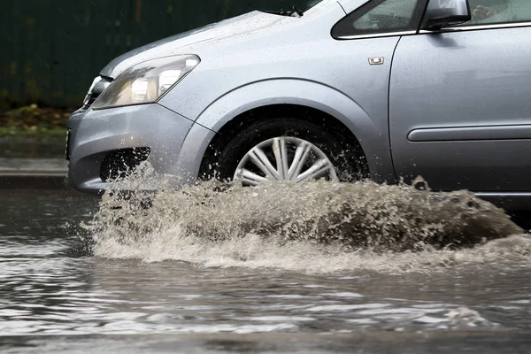 在洪水泛滥的道路上，汽车在大雨中行驶 免版税图库图片