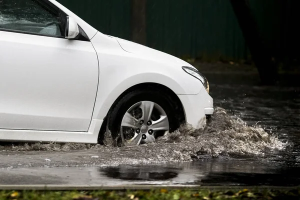 在洪水泛滥的道路上，汽车在大雨中行驶 免版税图库照片