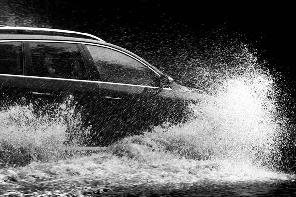 在洪水泛滥的道路上，汽车在大雨中行驶 图库照片