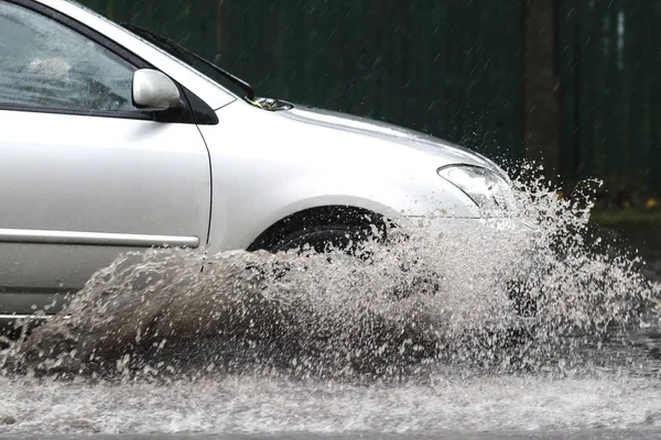 在洪水泛滥的道路上，汽车在大雨中行驶 图库照片