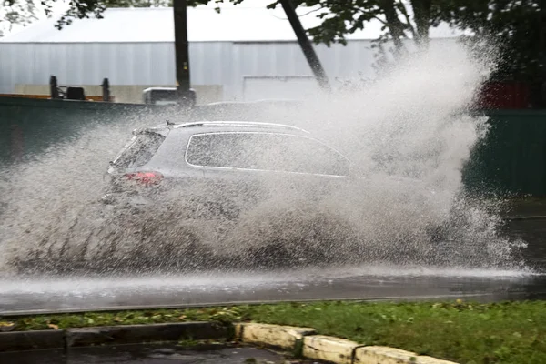 在洪水泛滥的道路上，汽车在大雨中行驶 图库图片
