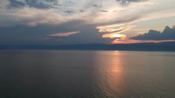 De drone vliegt geleidelijk over het wateroppervlak. Het Baikalmeer, de natuur van de Russische Federatie. Panoramische luchtfoto 's van zonsondergang. — Stockvideo