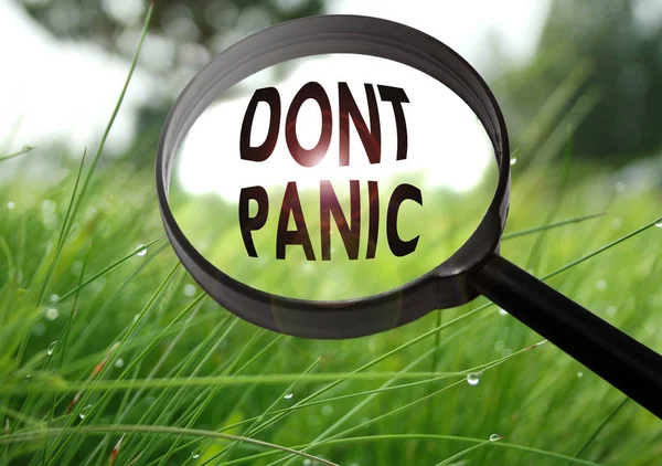 Memperbesar kaca dengan kata jangan panik pada latar belakang rumput. Fokus selektif — Stok Foto