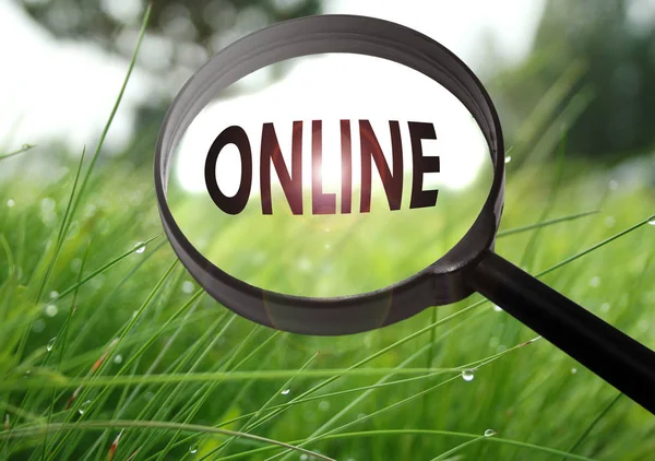 Magnifying glass with the word online on grass background. Selective focus — Stock Photo, Image