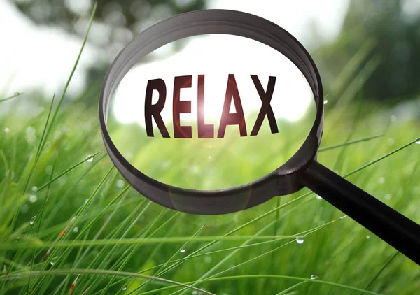 Lente d'ingrandimento con la parola relax su sfondo erba. Focus selettivo — Foto Stock