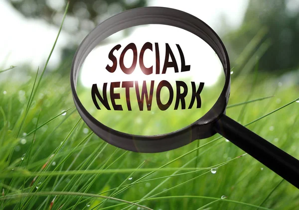 Förstoringsglas med ordet sociala nätverk på gräs bakgrund. Selektivt fokus — Stockfoto