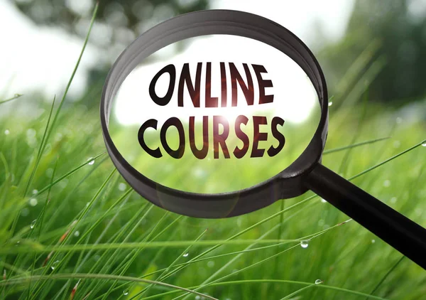 Lupa con la palabra cursos en línea sobre hierba de fondo. Enfoque selectivo — Foto de Stock