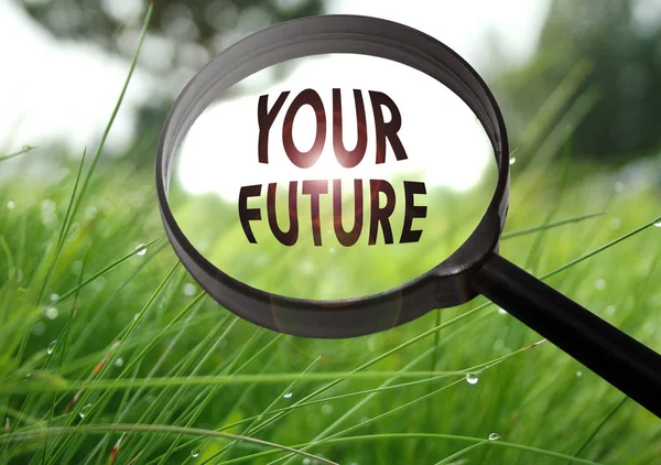Förstoringsglas med ordet din framtid på gräs bakgrund. Selektivt fokus — Stockfoto