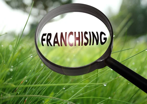 Μεγεθυντικός φακός με το franchising λέξη σε χόρτο φόντο. Επιλεκτική εστίαση — Φωτογραφία Αρχείου