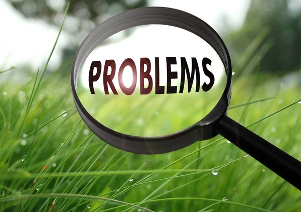 Vergrootglas met het woord problemen op gras achtergrond. Selectieve aandacht — Stockfoto