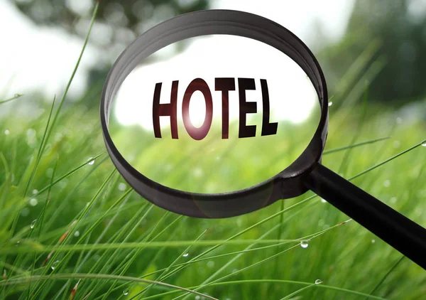 草の背景に単語のホテル付きの虫眼鏡。選択と集中 — ストック写真