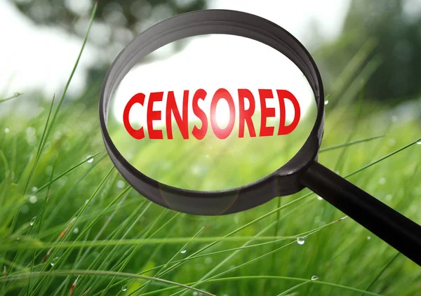 Увеличительное стекло со словом цензура на фоне травы. Селективный фокус — стоковое фото
