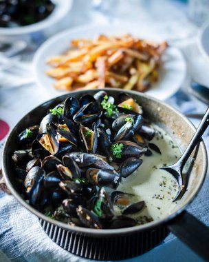 Moules kızartması. Patates kızartmalı istiridye. Siyah tavada patates kızartması ve arka planda patates kızartması..