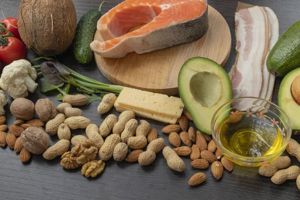 Keto diyeti. Sağlıklı gıda seti. Balık, fındık, protein, sebze ve meyve. Siyah tahta bir arka planda. Yukarıdan bak. Metin için boş alan.