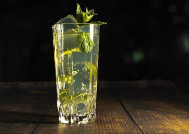 Siyah arka planda cam bir tankta naneli ve buzlu mojito kokteyli. Soğuk yaz içeceği ve kokteyl